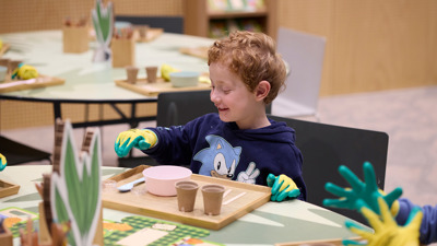 Child sitting at a table planting seeds. 